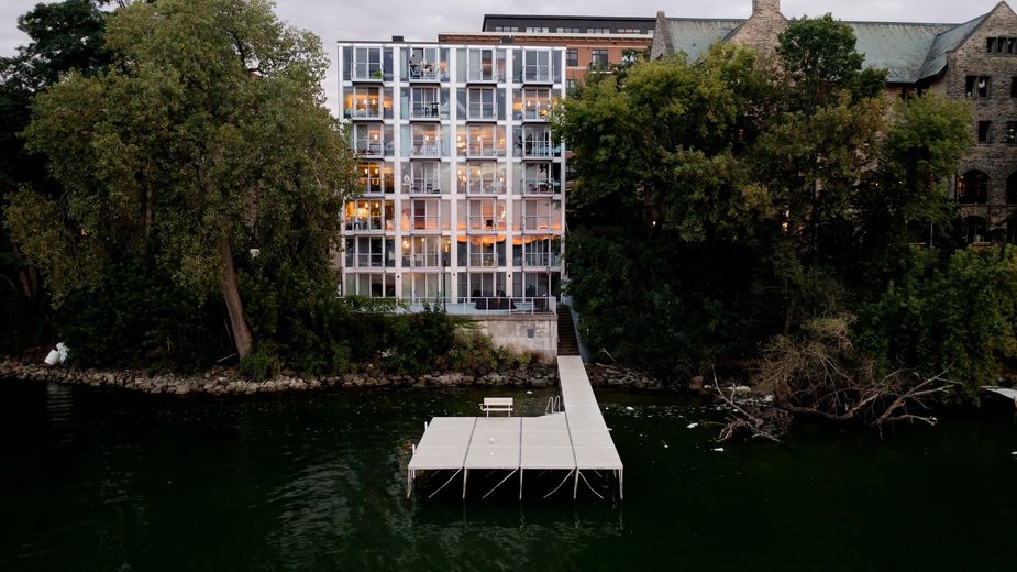 An aerial view of a building next to a body of water with a dock in front of it.