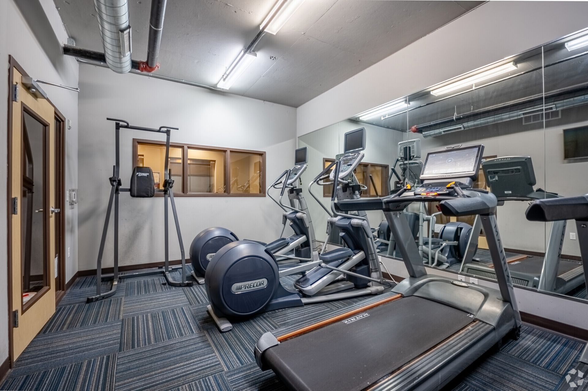 A gym with a treadmill , elliptical , and other exercise equipment.