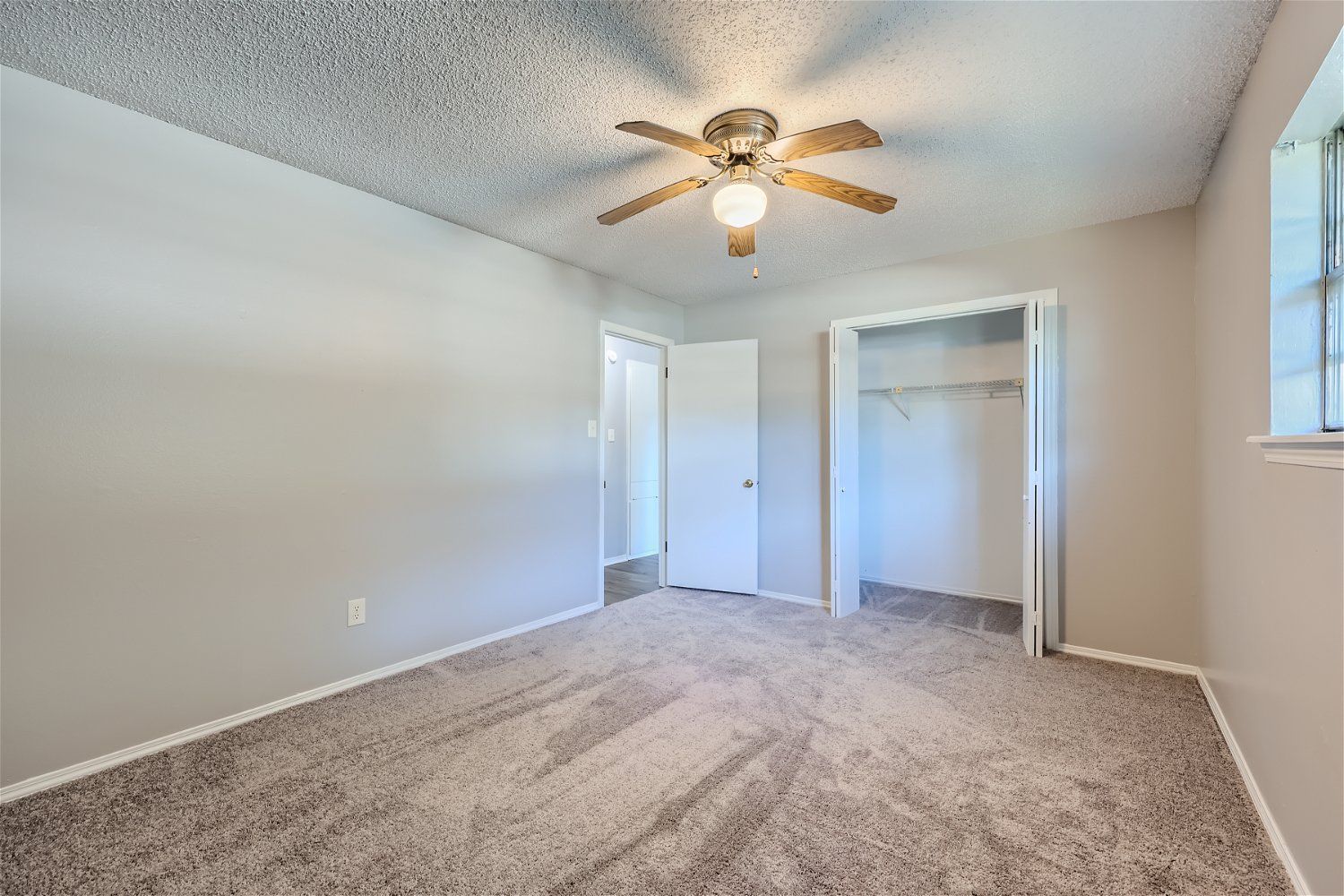 Bedroom with gray walls, beige carpet, ceiling fan, and closet.