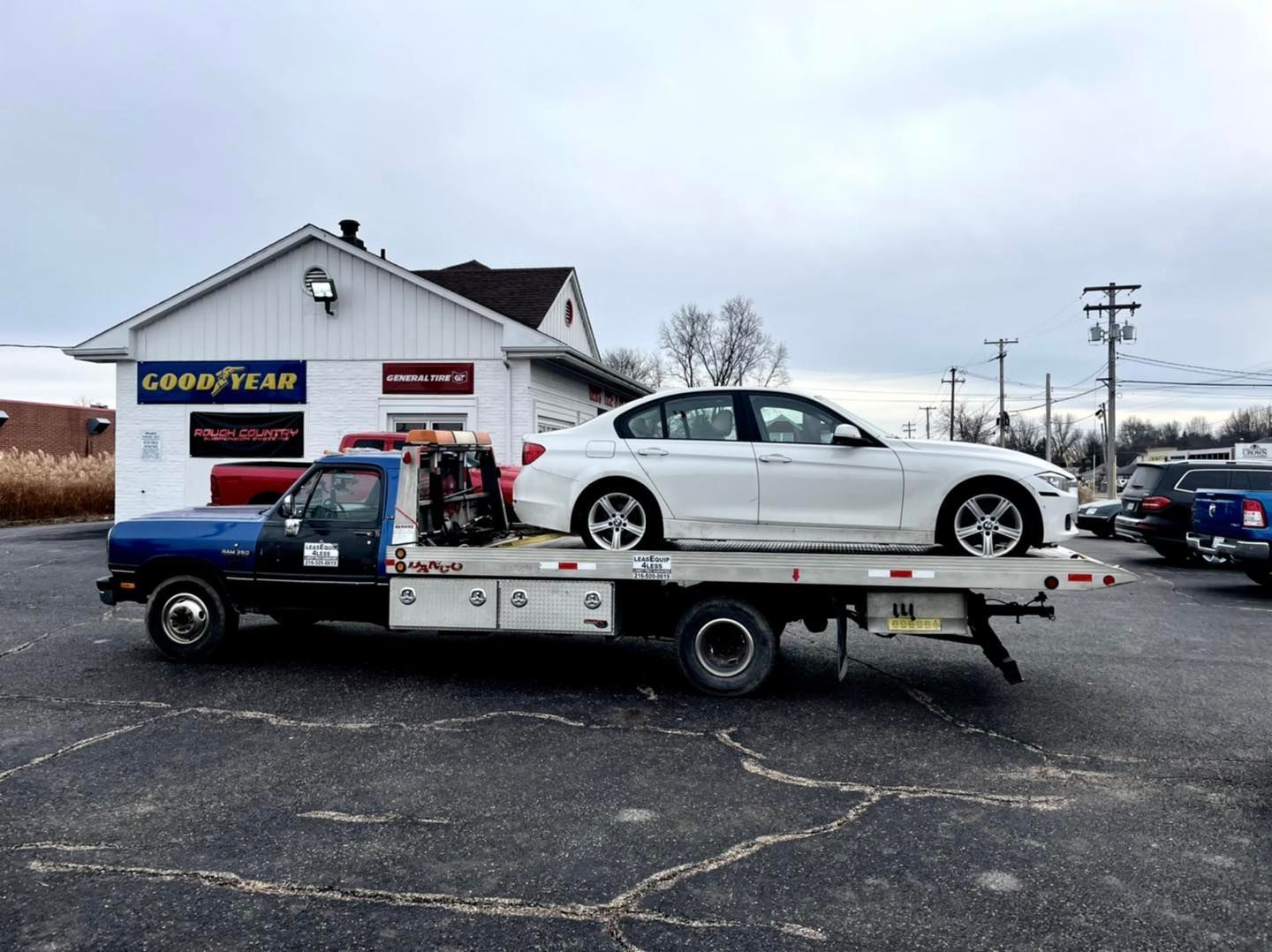 Tow truck lifting a large, round object, likely a sculpture or container, outdoors.