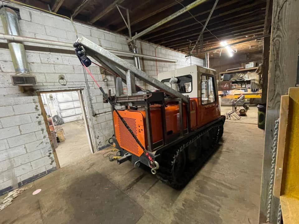 Orange tracked vehicle with a crane inside a garage.