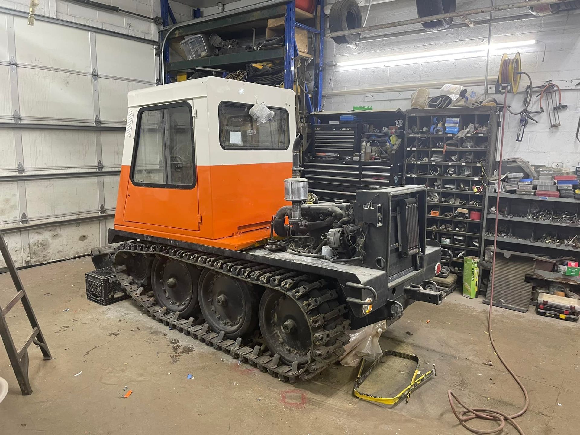 Truck loading large log on a trailer in a grassy area with trees and blue sky.