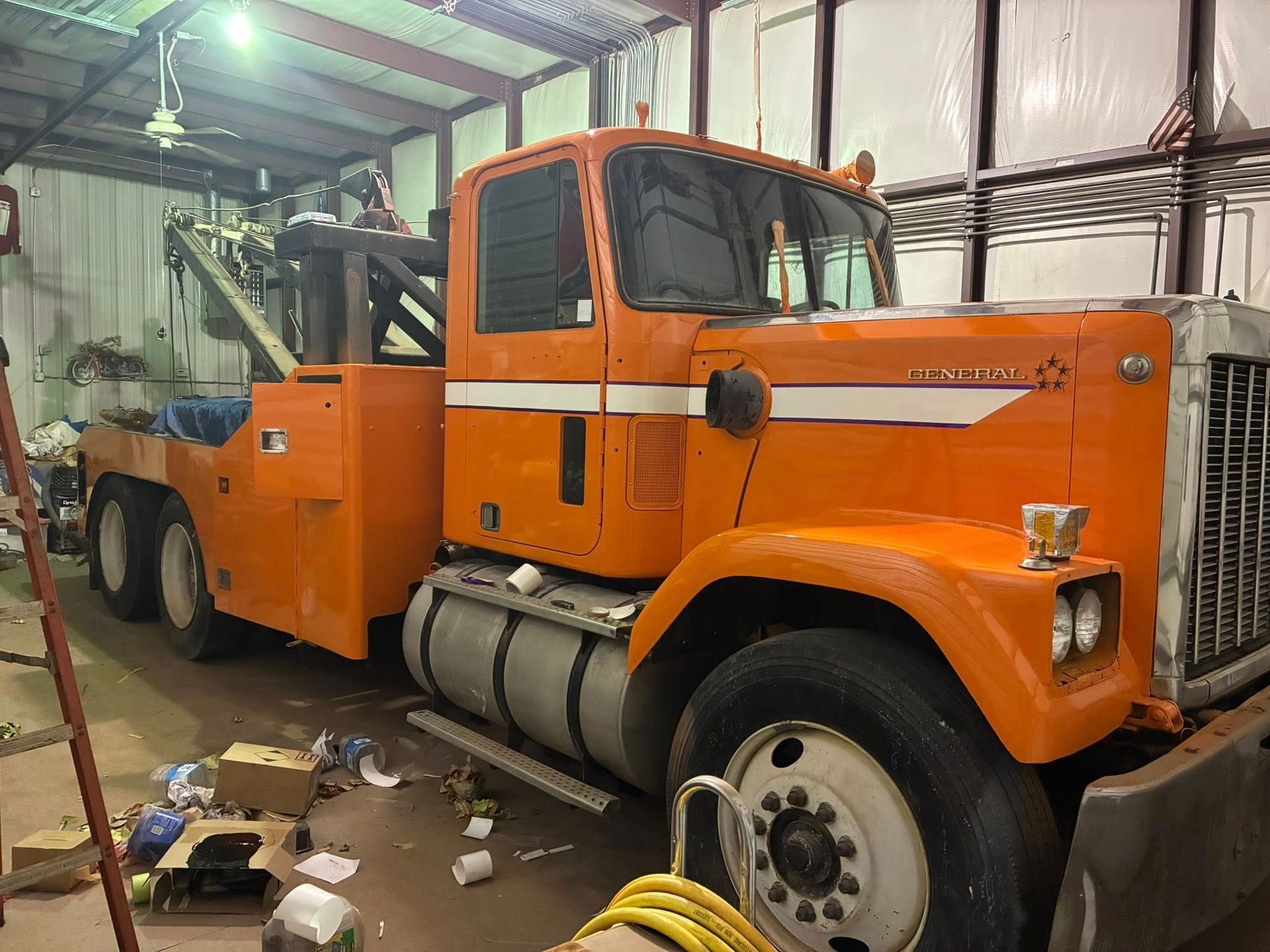 Orange tow truck in a cluttered garage.