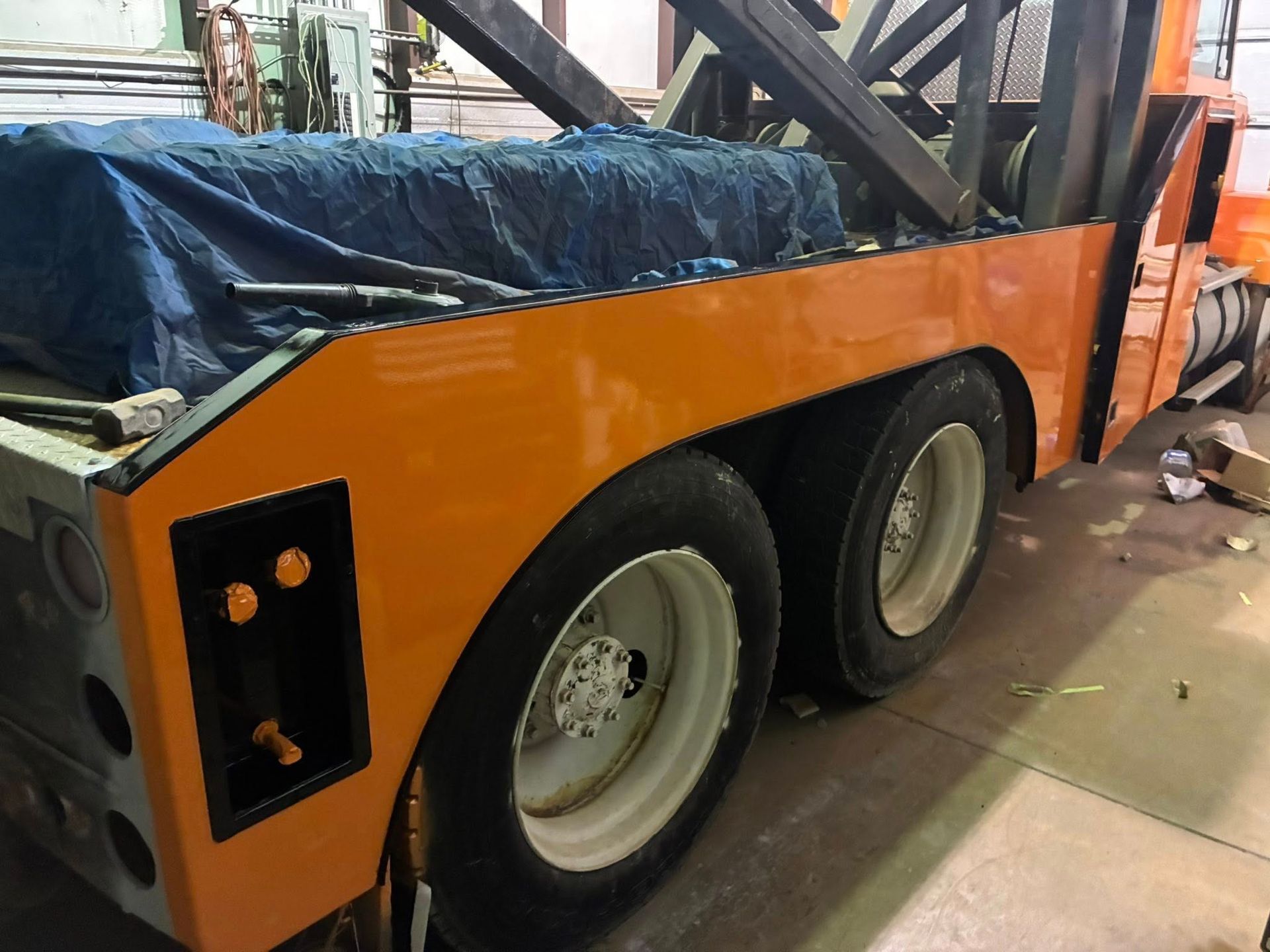 Orange tow truck with dual rear wheels. Black accents, blue tarp, and white rims.