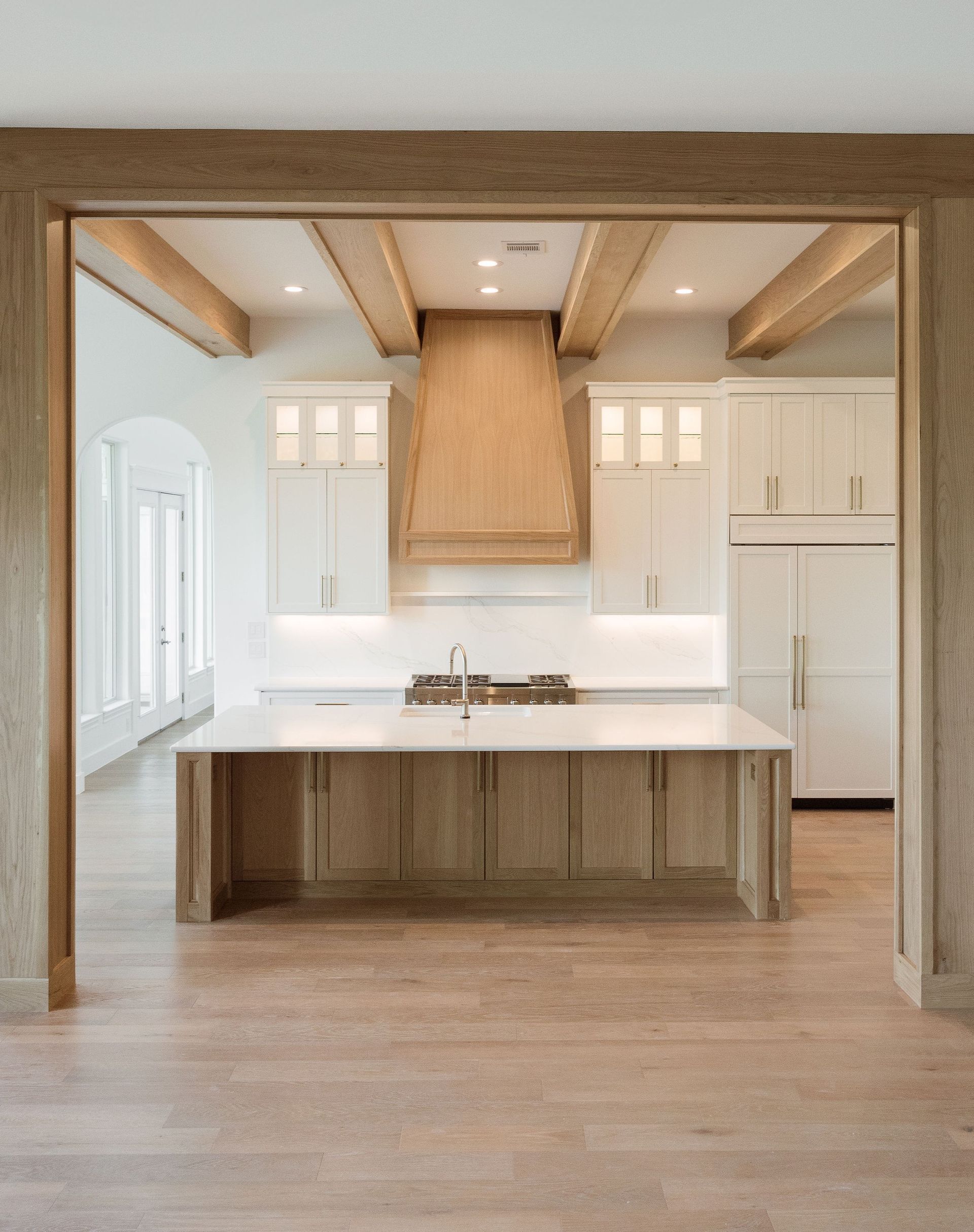 Light wood kitchen with island, white cabinets, and light countertops.