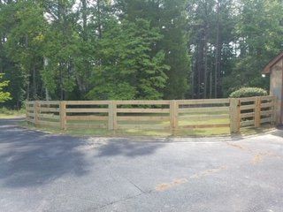 A wooden fence is surrounding a lush green field.