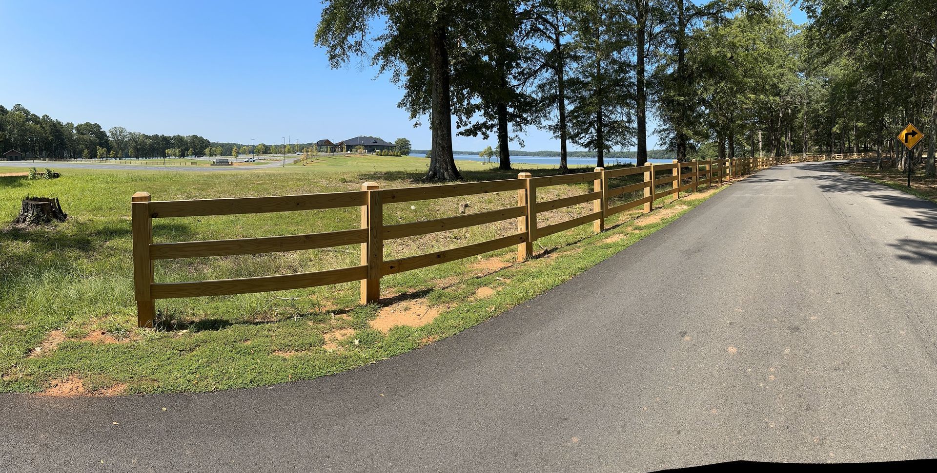 A wooden fence is along the side of a road.