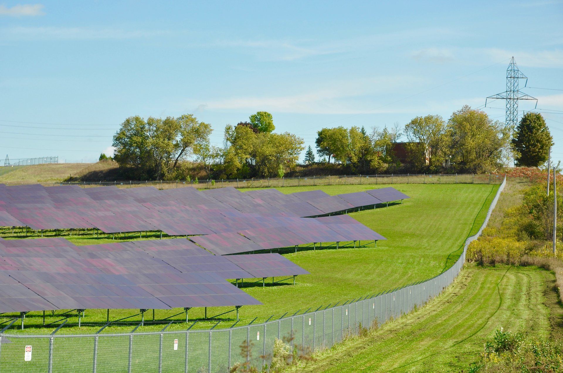 A fence surrounds a field of solar panels.