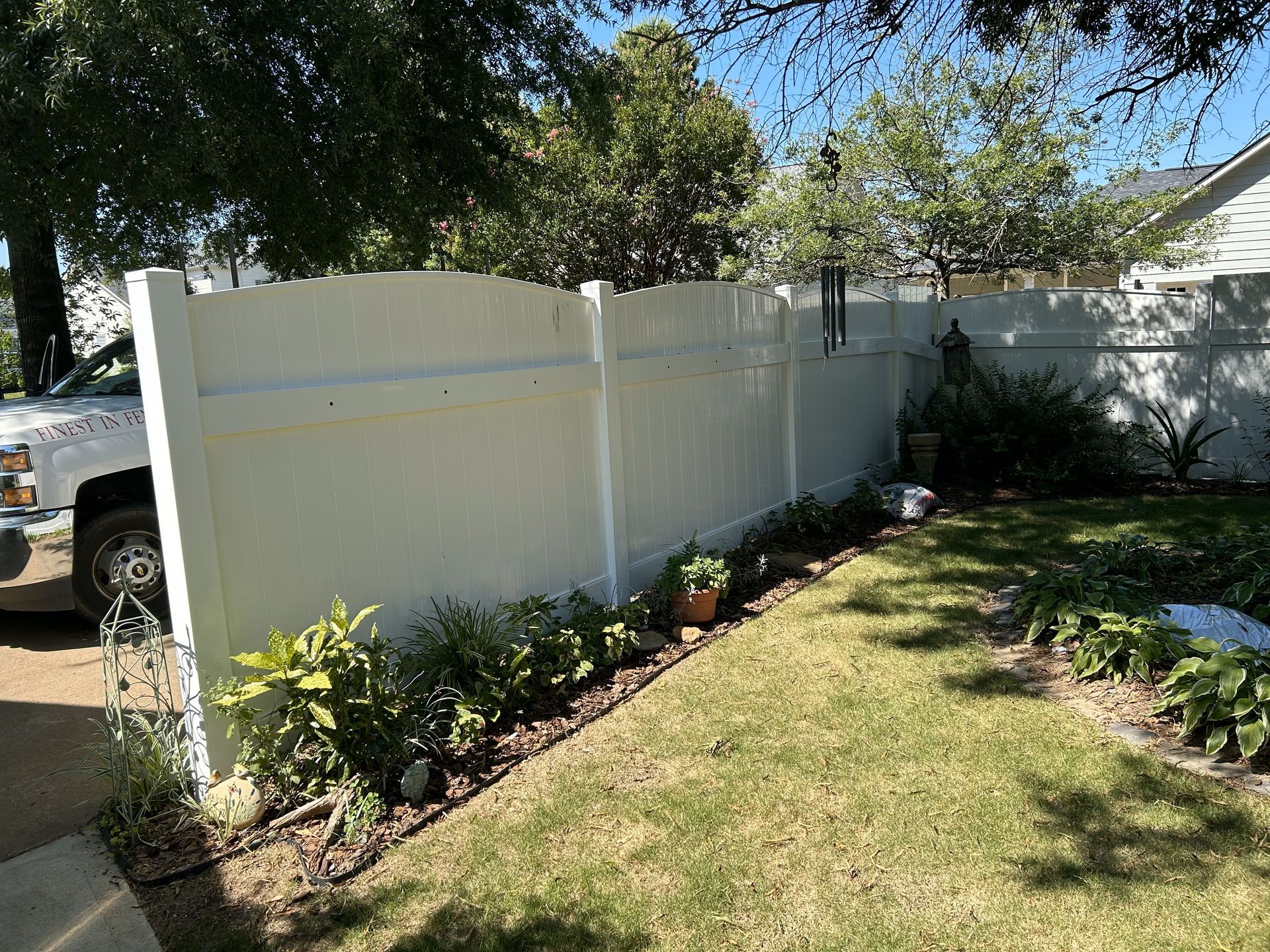 A white fence is in the middle of a lush green yard.