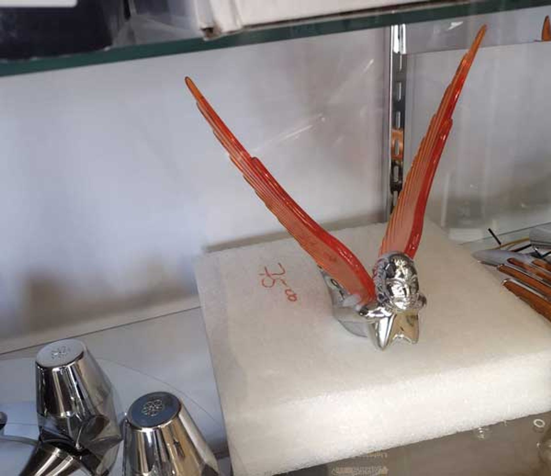 A statue of a bird with red wings sits on a white block