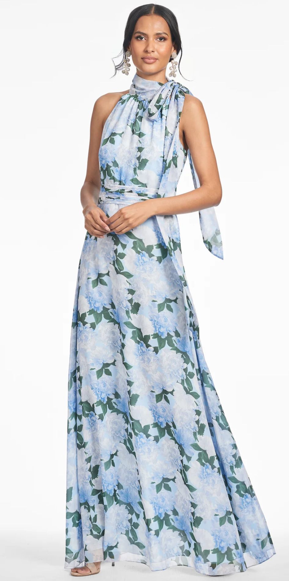 A woman in a black dress is standing in the sand.