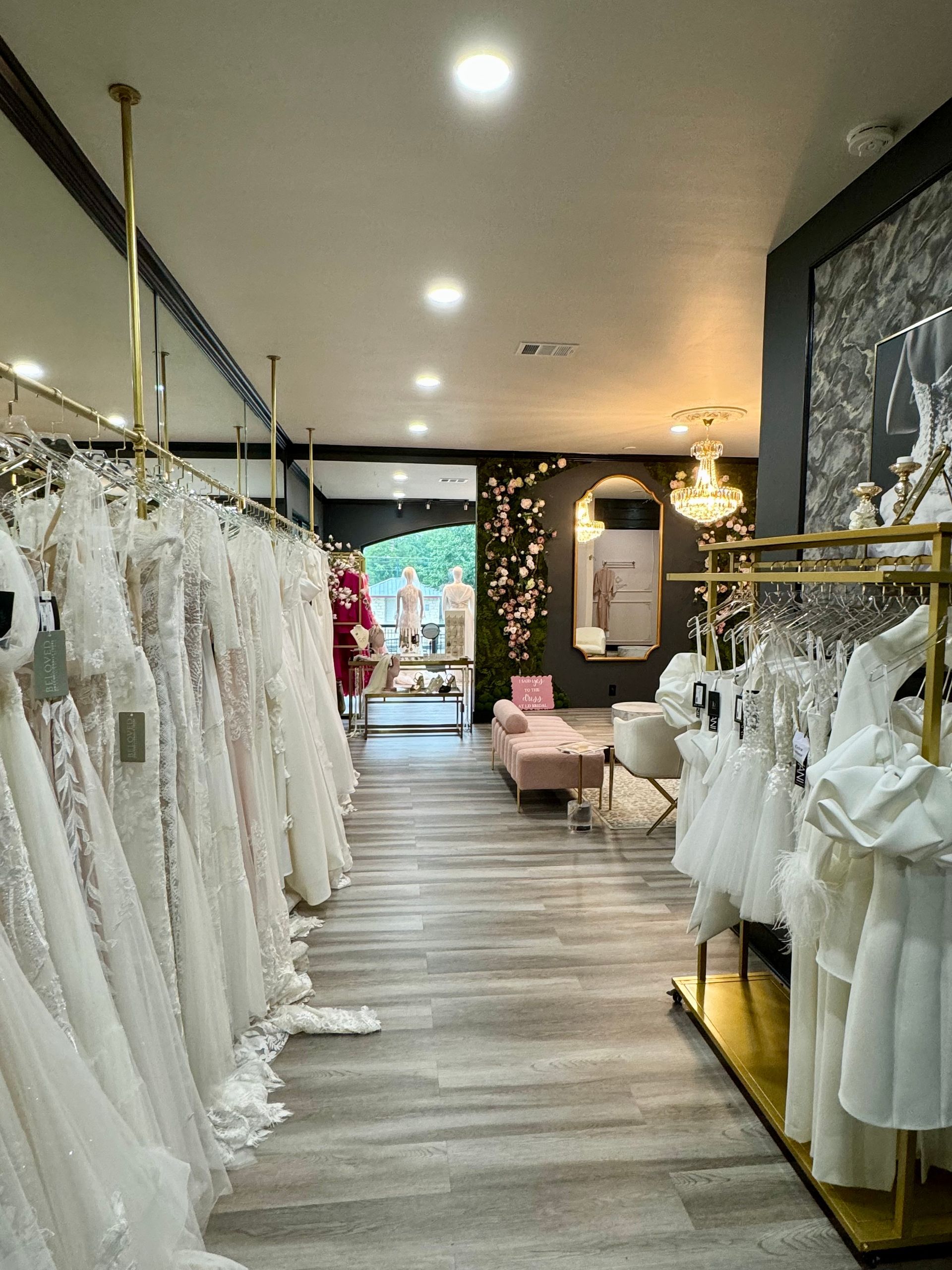 A long hallway filled with lots of white dresses hanging on racks.