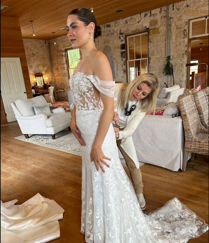 A woman is trying on a wedding dress in a bridal shop.