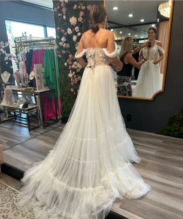 A woman is trying on a wedding dress in a bridal shop.
