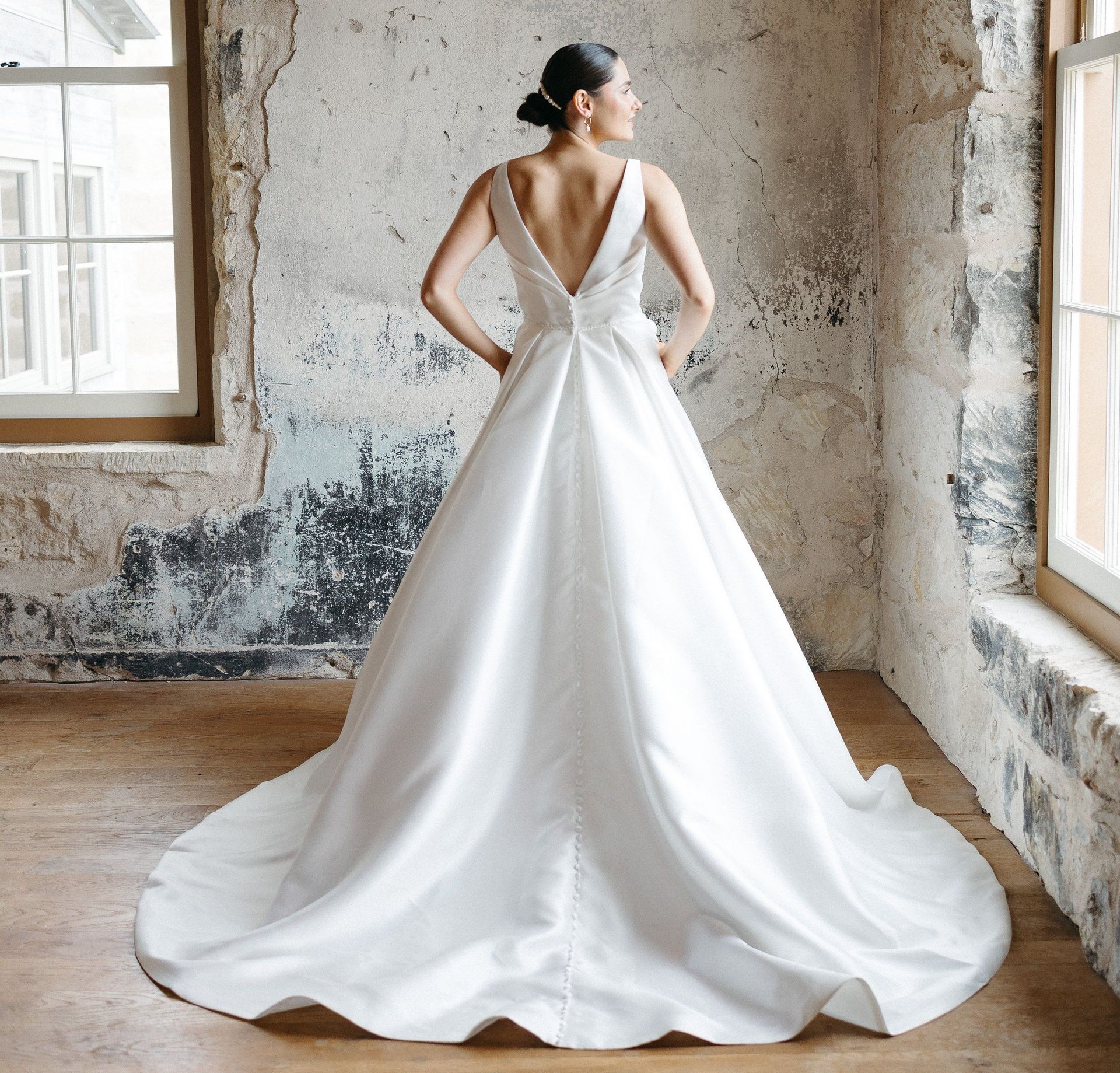A woman in a white wedding dress is standing in front of a mountain.