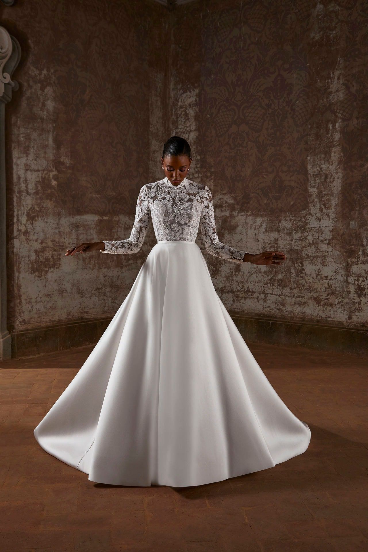 A woman is wearing a white wedding dress with long sleeves.