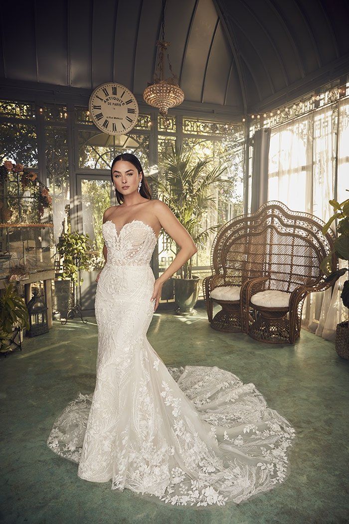 A woman in a wedding dress is standing in a greenhouse.