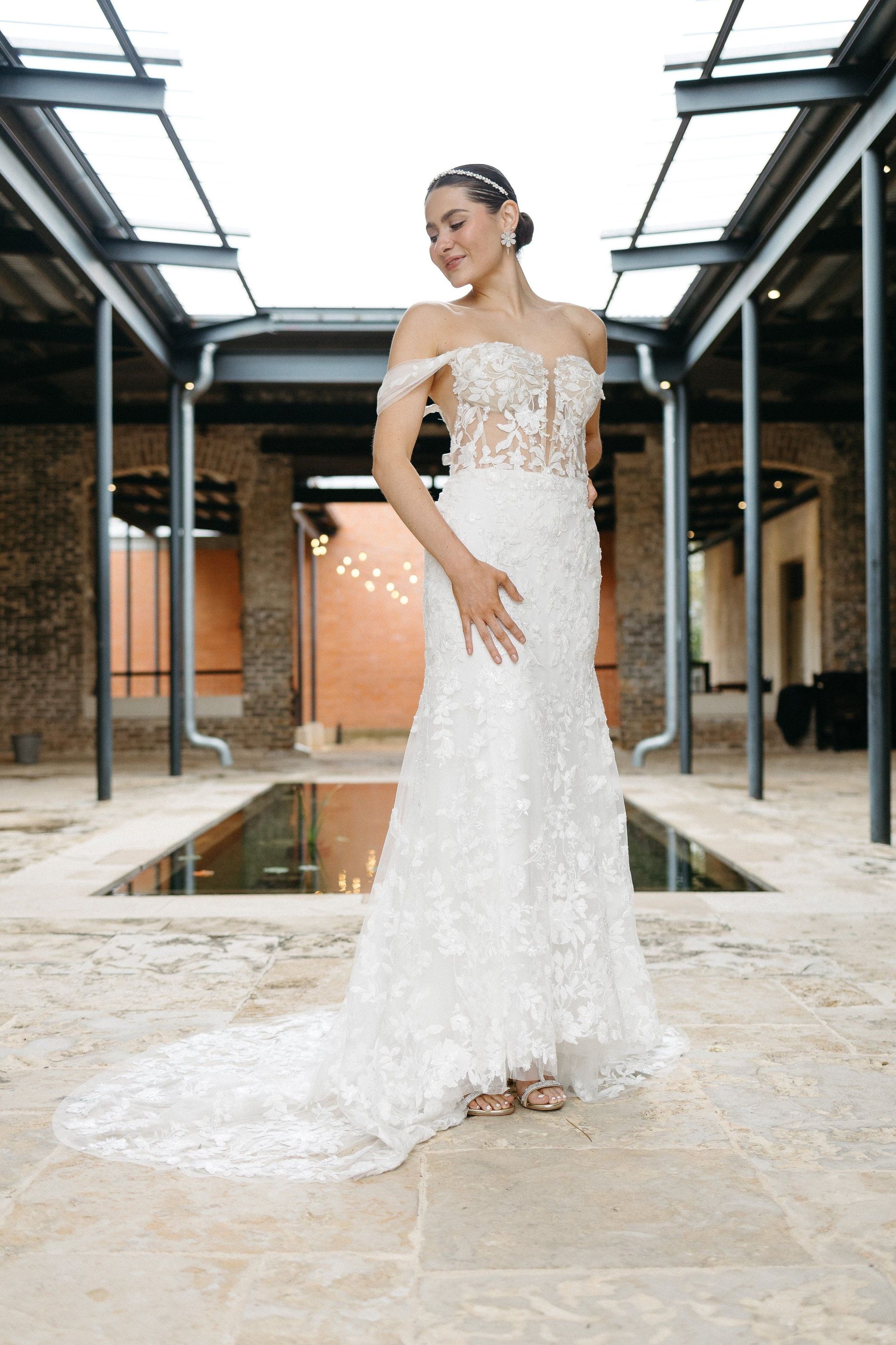 A woman in a white wedding dress is standing in front of a pool.