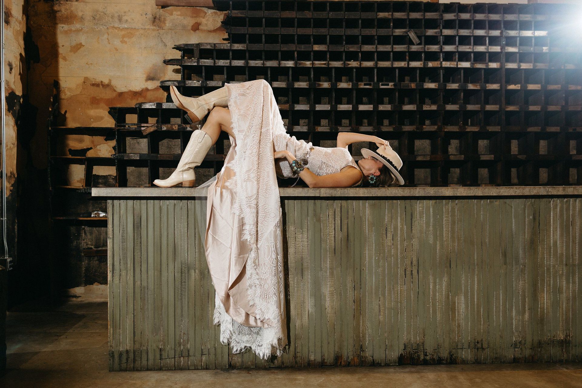 A woman in a wedding dress is laying on a wooden counter.