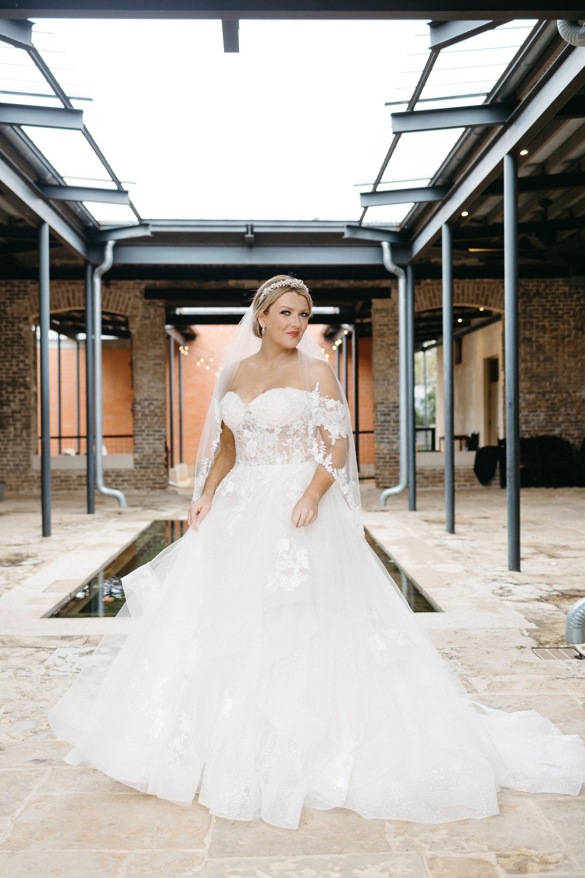 A woman in a wedding dress and veil is standing in front of a fountain.