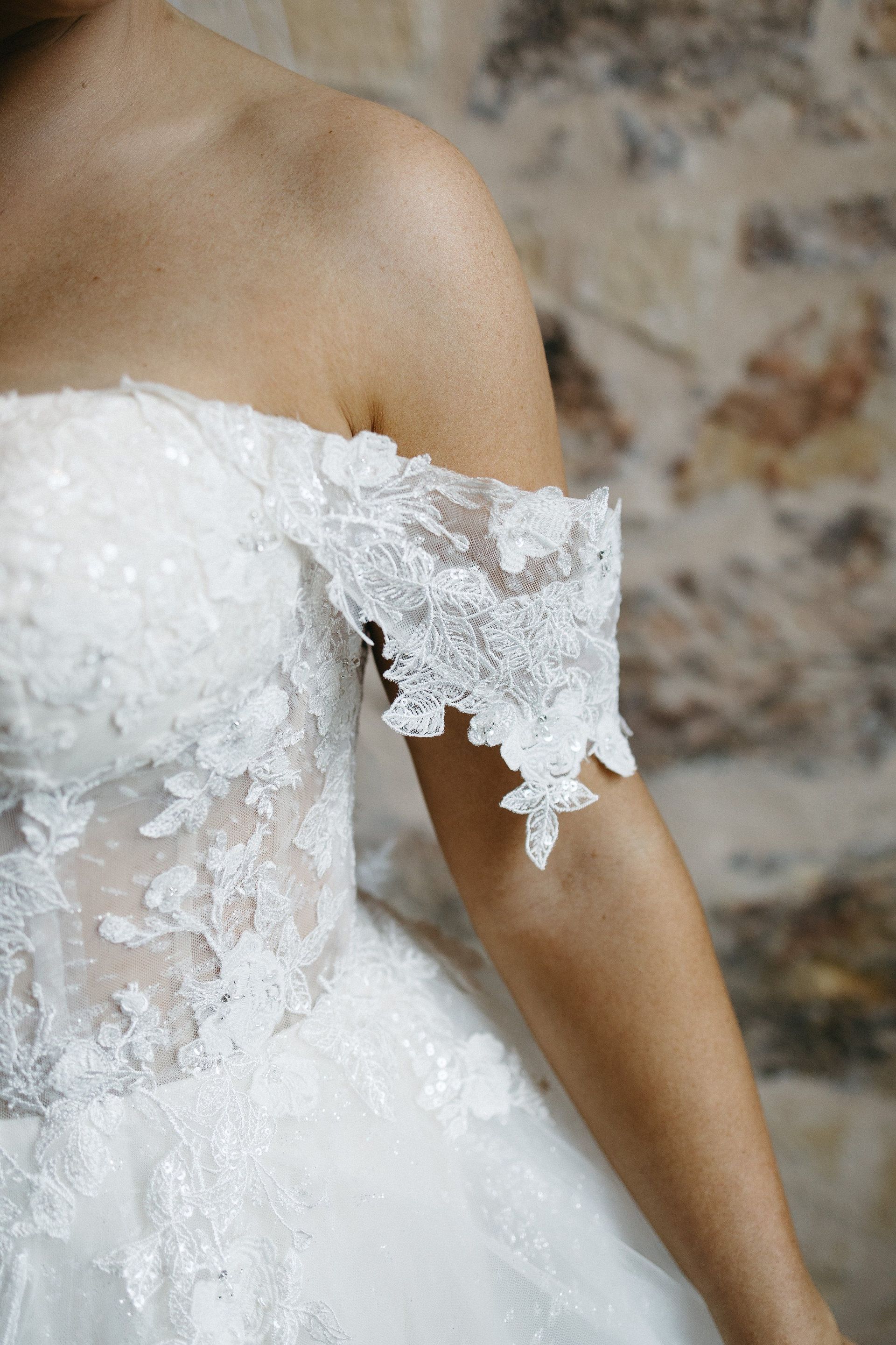 A close up of a woman wearing a white lace wedding dress.
