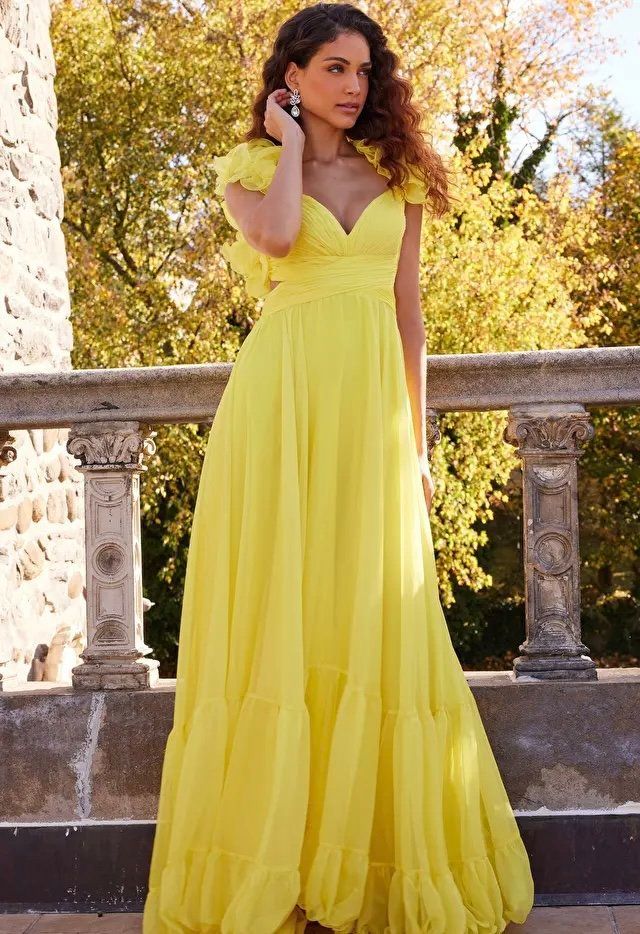 A woman in a long yellow dress is standing on a balcony.