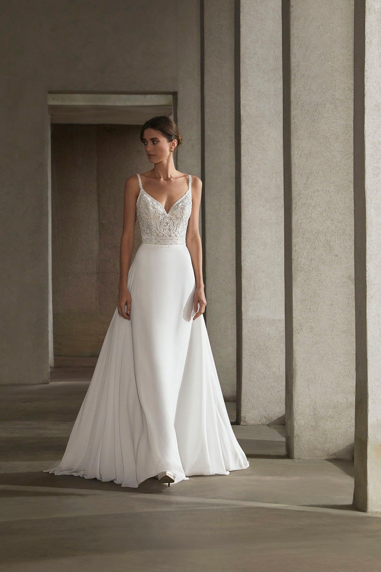 A woman in a white wedding dress is standing in front of a building.
