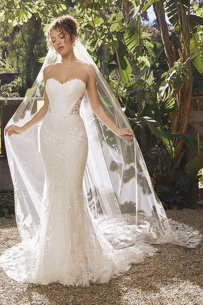 A woman in a wedding dress and veil is standing in a garden.