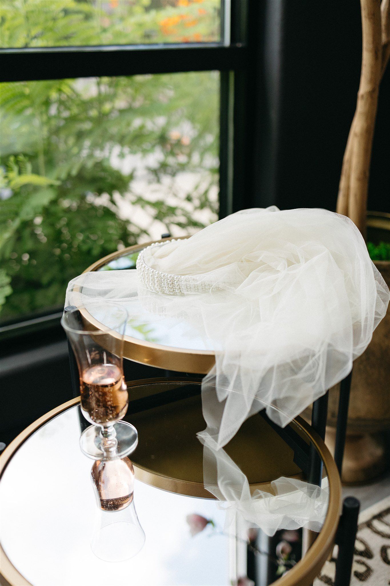 A veil is sitting on top of a table next to a glass of champagne.