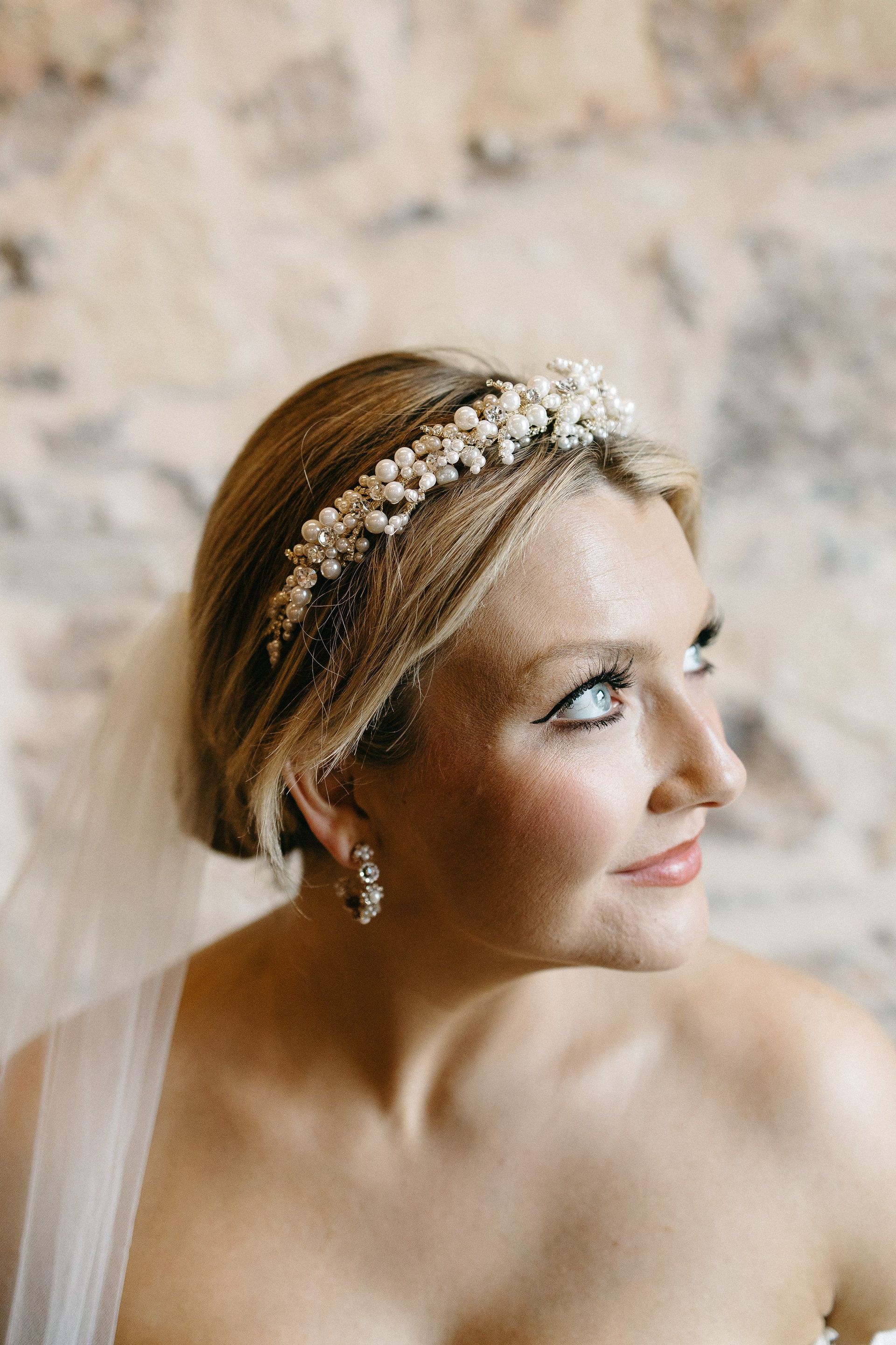 The bride is wearing a veil and a headband with pearls.