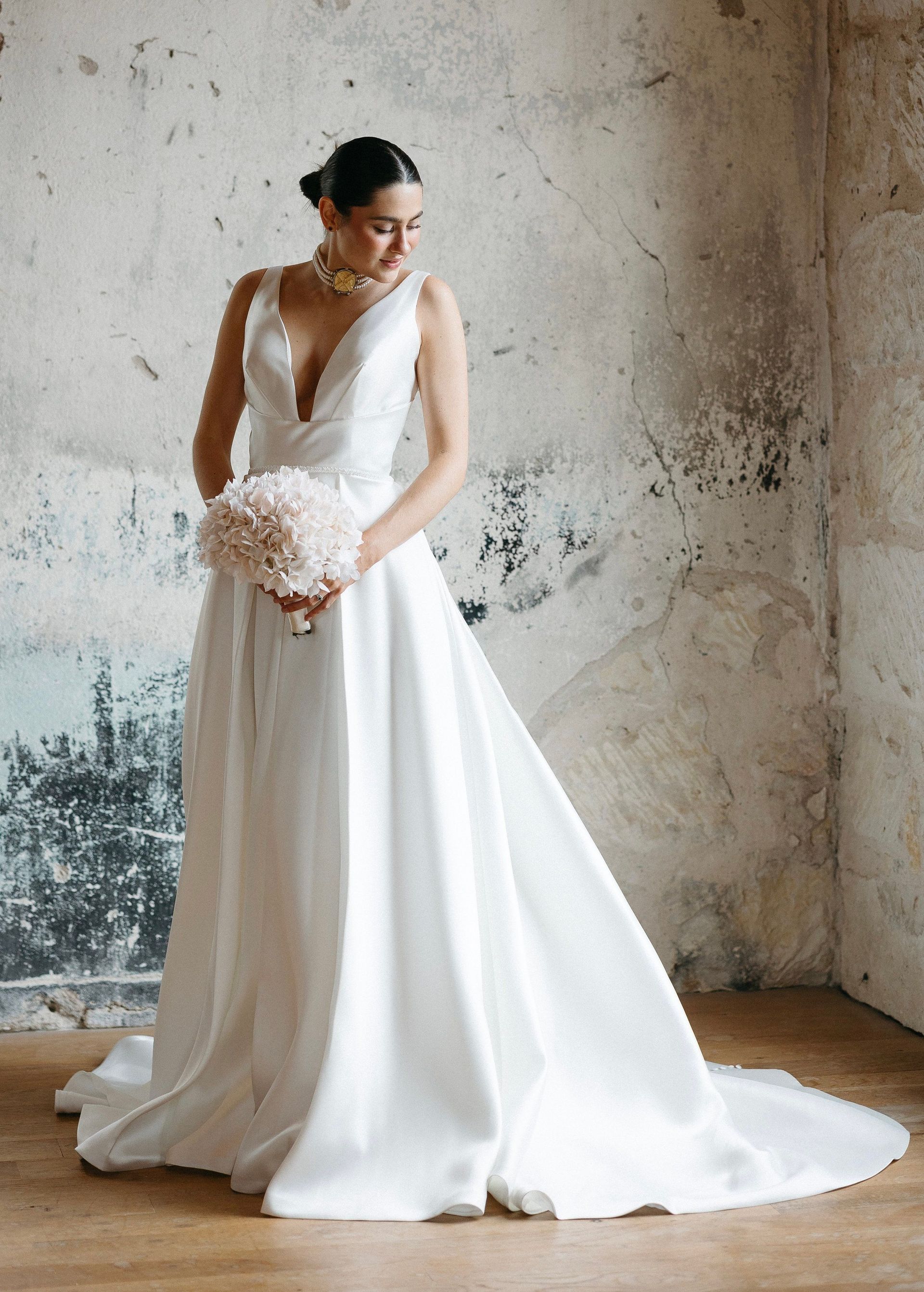 The bride is wearing a white wedding dress and holding a bouquet of flowers.
