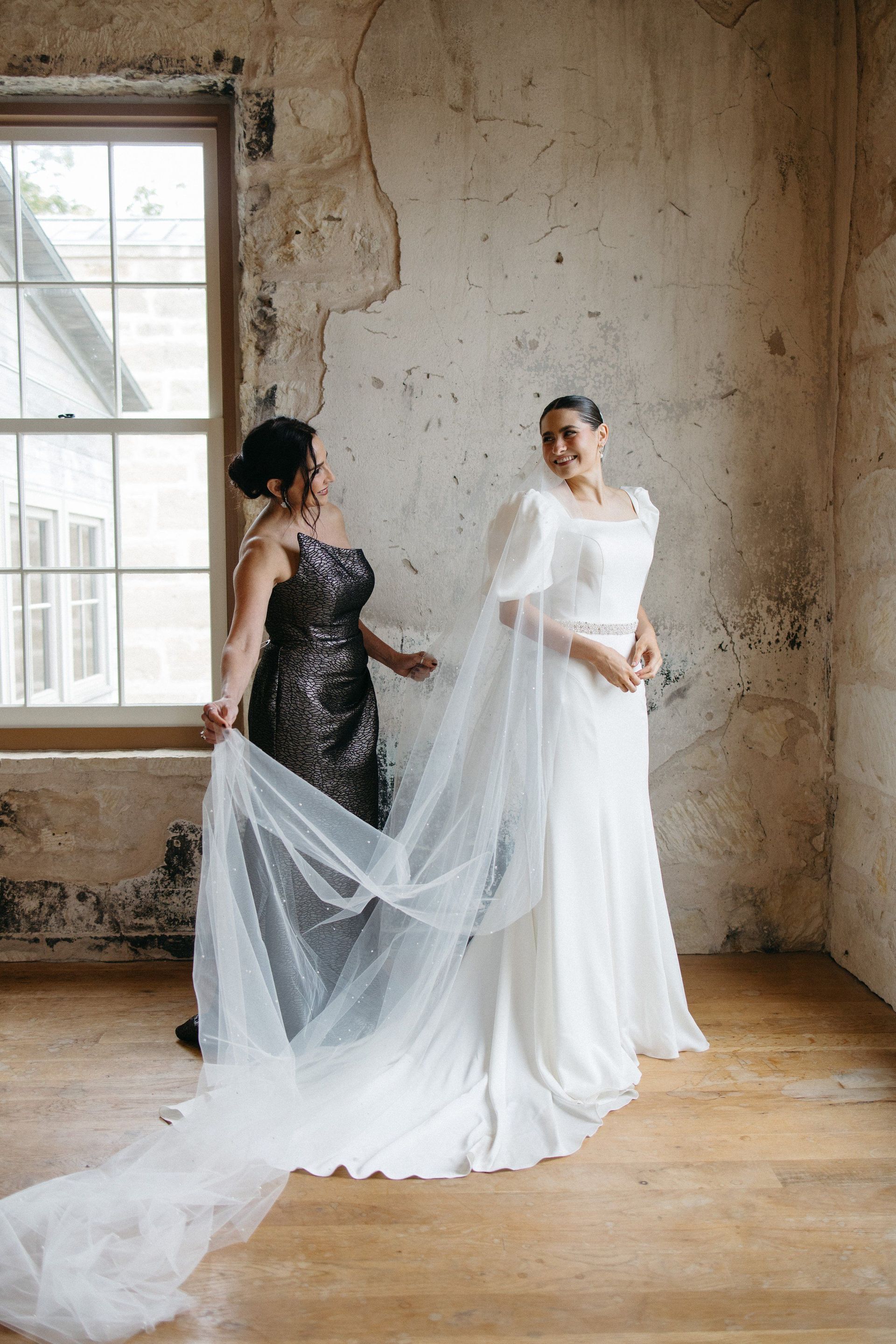 A bride and her mother are standing next to each other in a room.