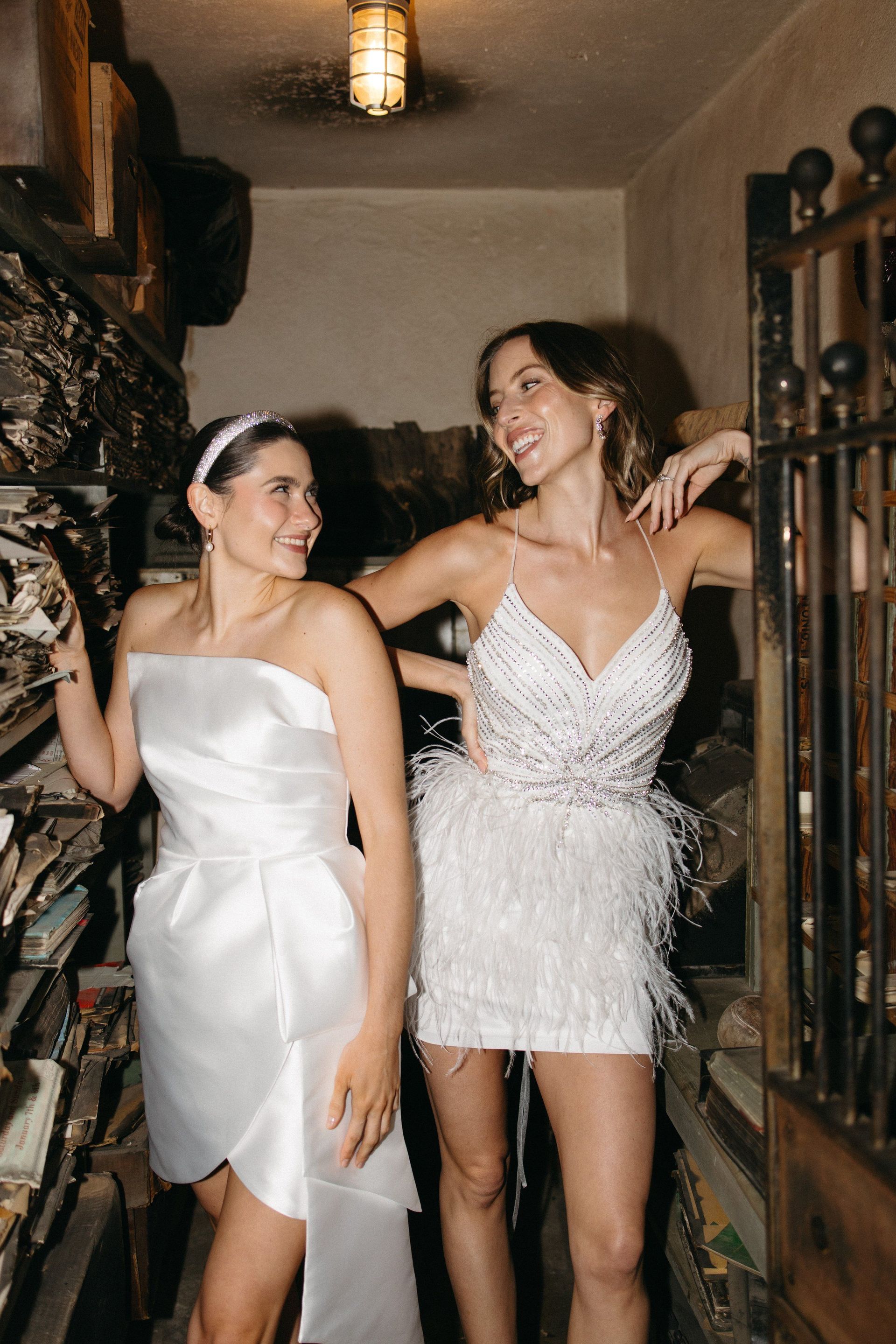 Two women in white dresses are standing next to each other in a room.