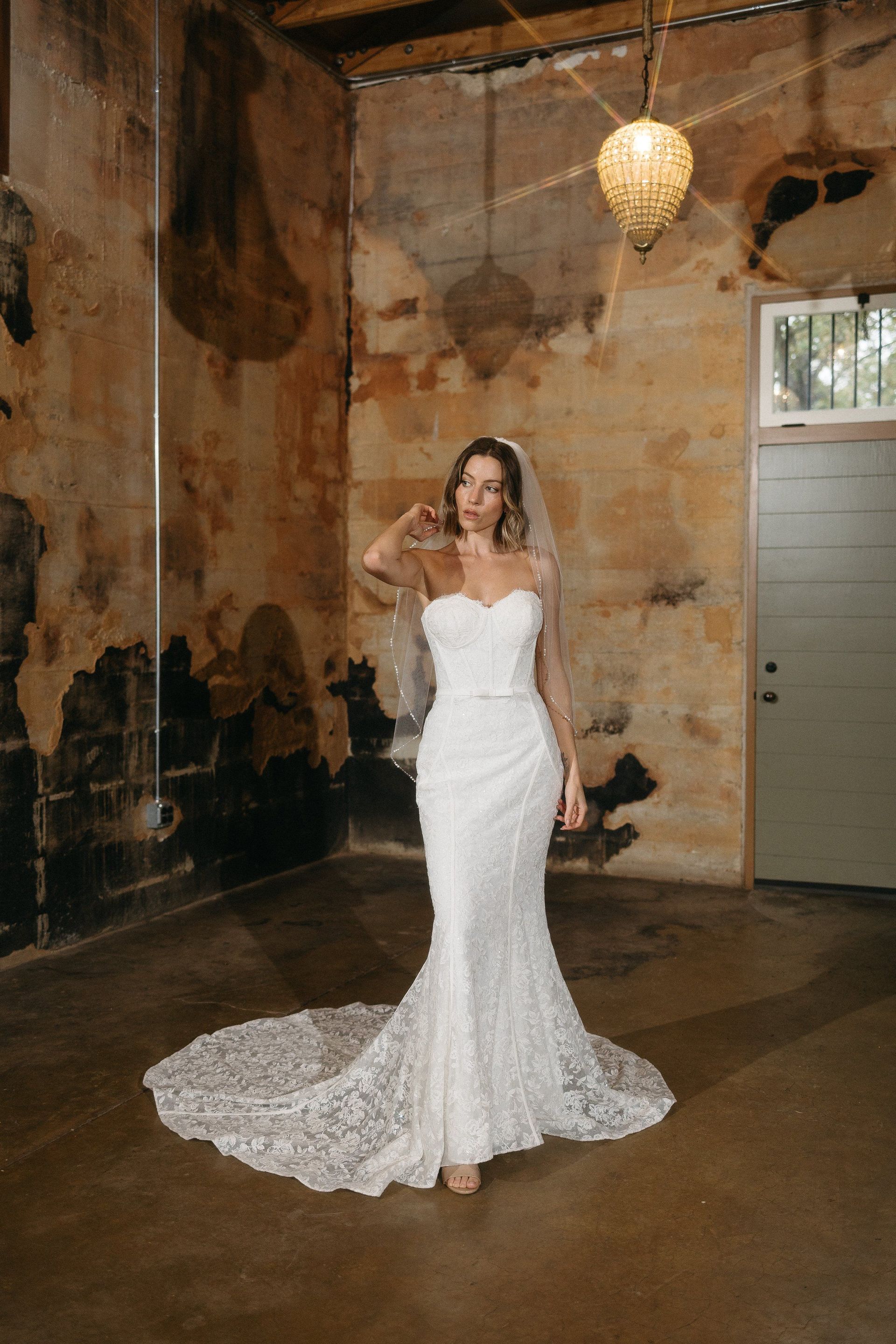 A woman in a wedding dress and veil is standing in a room.