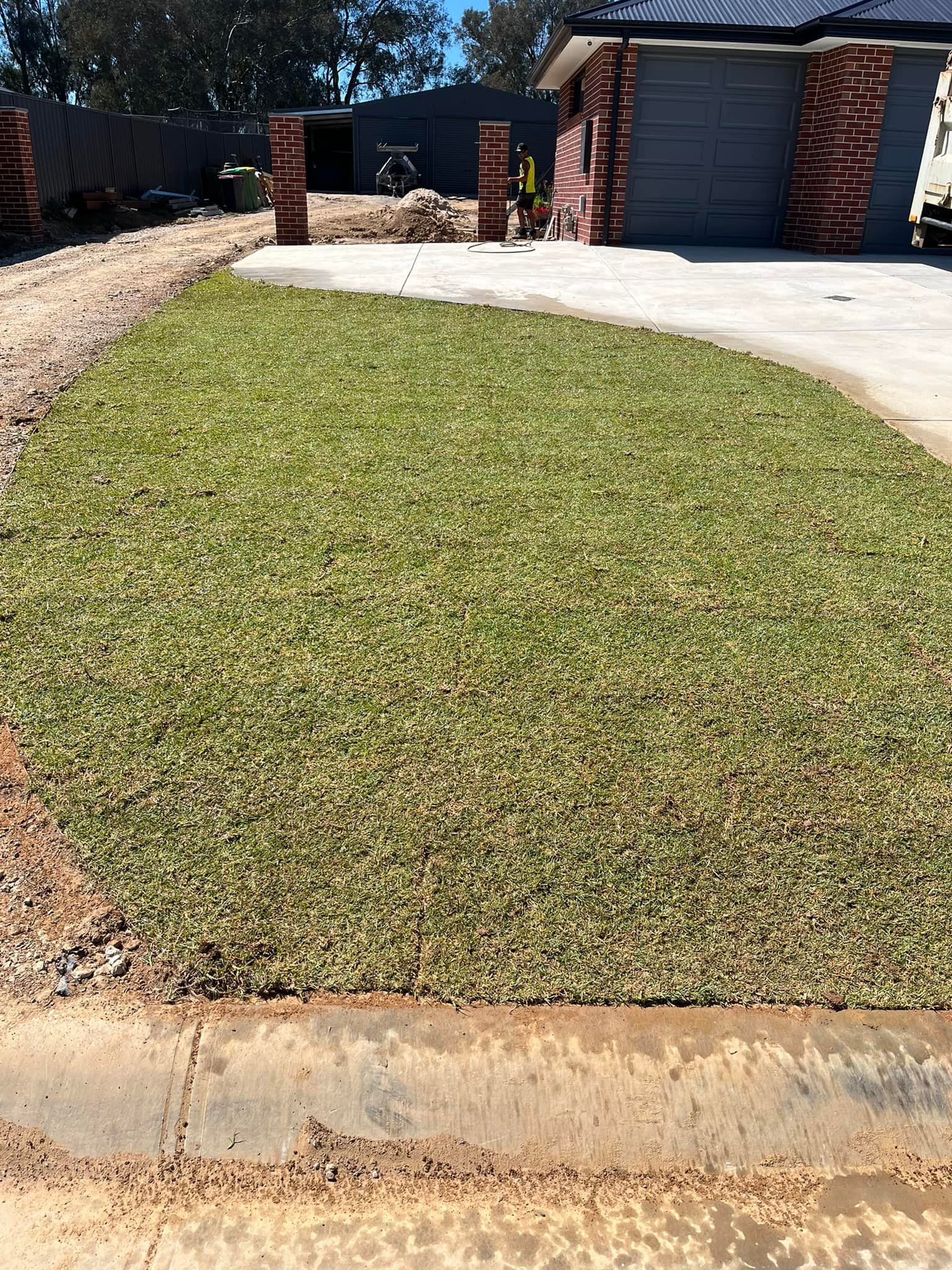 Green Lawn Bordered by Curb, Brick Pillars, Driveway, and House — Robbo's Hire In Thurgoona, NSW
