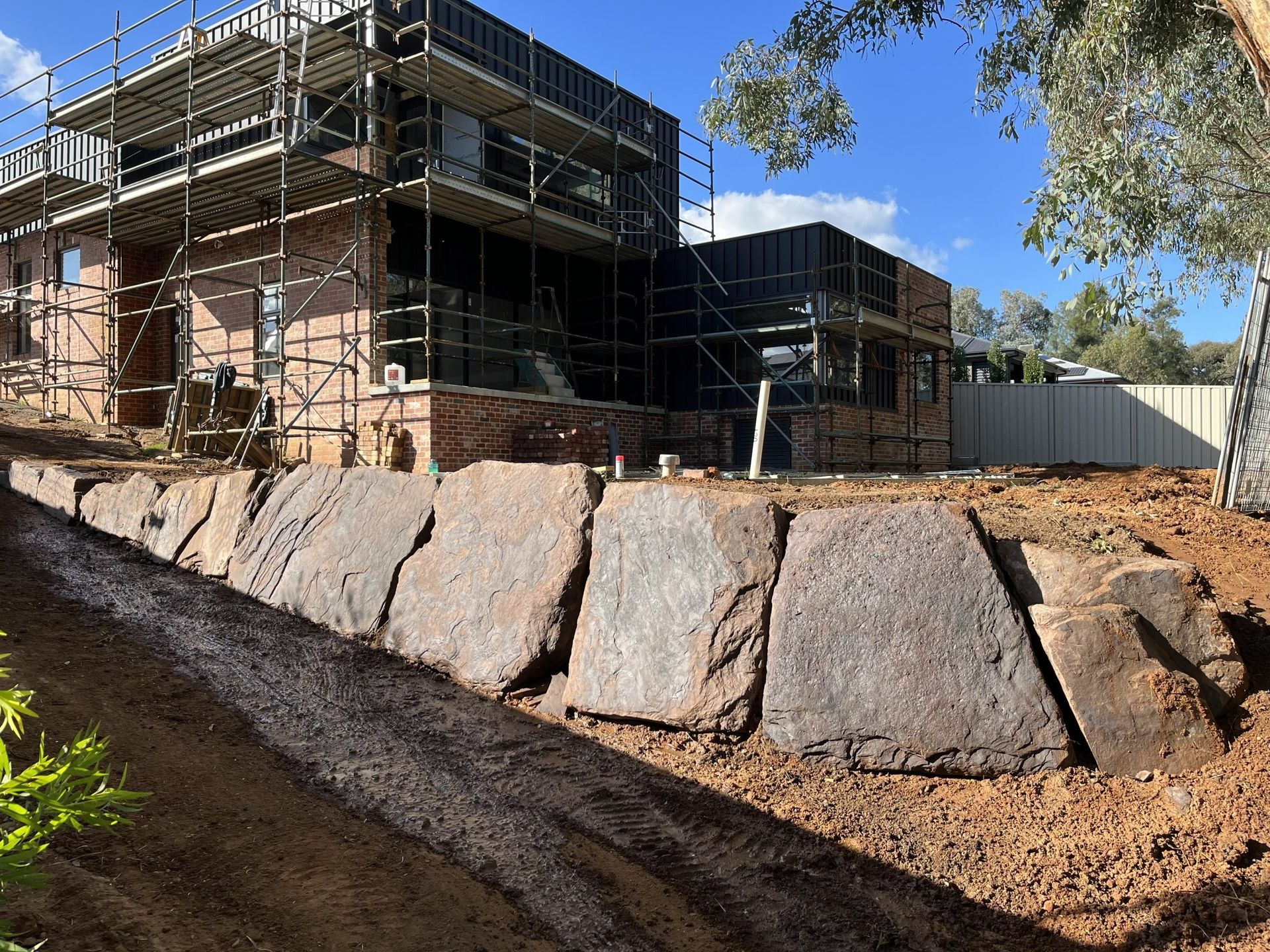 A Two-Story Building Under Construction with A Stone Retaining Wall — Robbo's Hire In Thurgoona, NSW