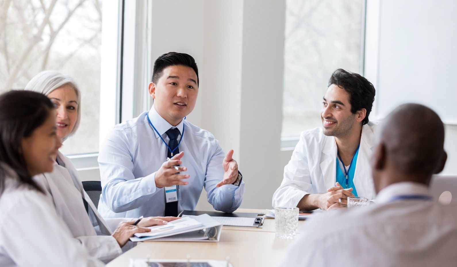 A group of doctors are sitting around a table having a meeting.