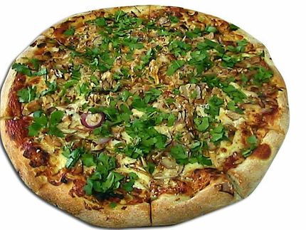 Pizza with toppings and green garnish.