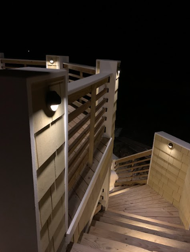 Wooden deck stairs with railing and built-in lights, at night.