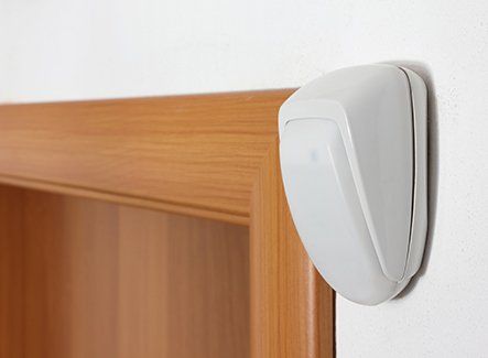 An alarm point mounted on an interior wall above a door