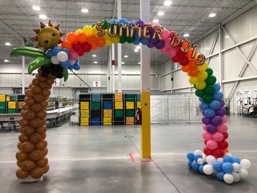 A balloon arch in a warehouse with a palm tree and sun.