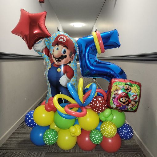 A mario balloon is surrounded by balloons in a hallway