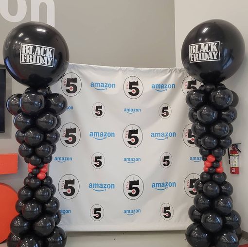 Two black friday balloons are sitting on top of black balloon columns