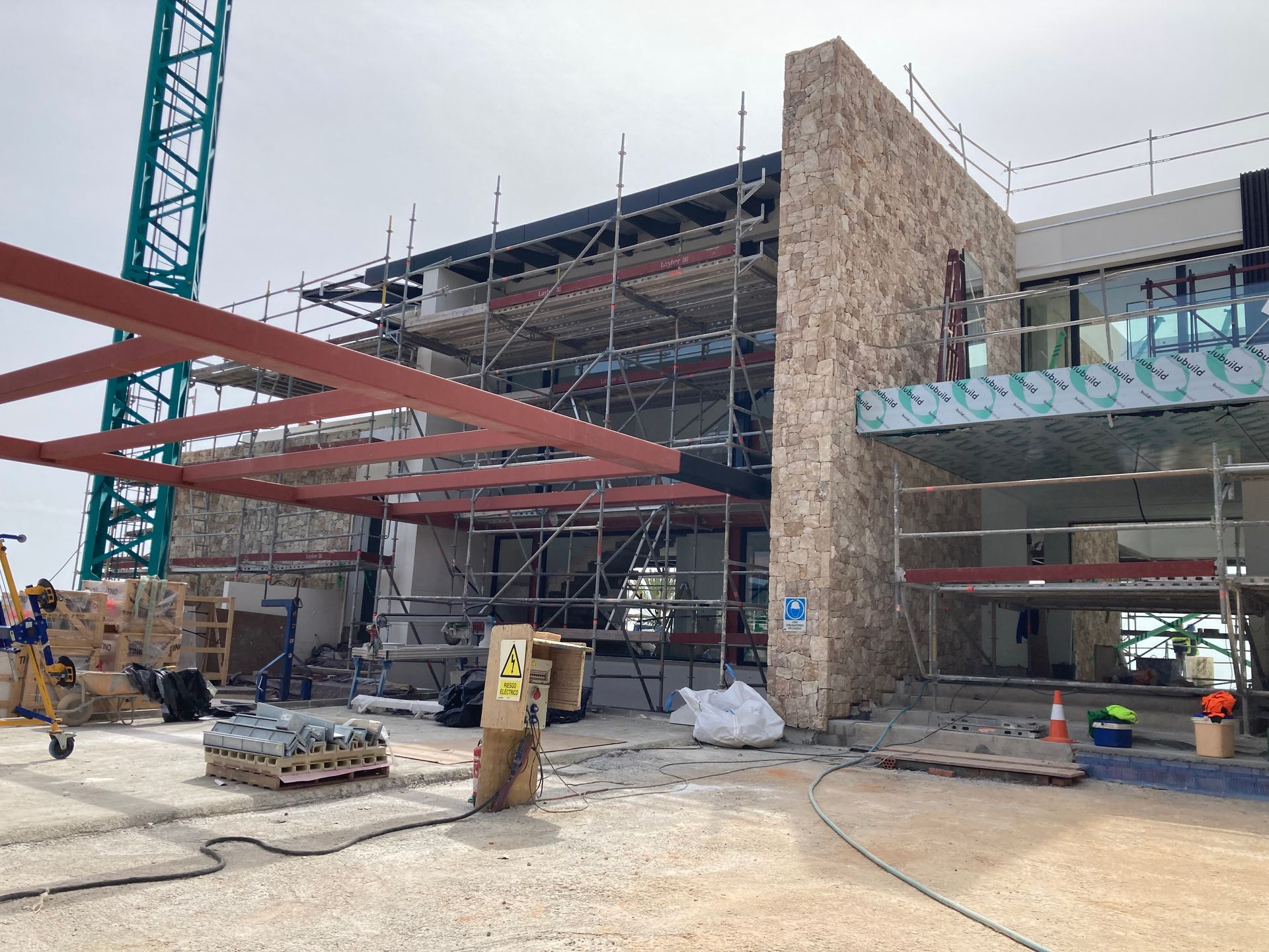 Obra con andamios, grúa y edificio con fachada de piedra.