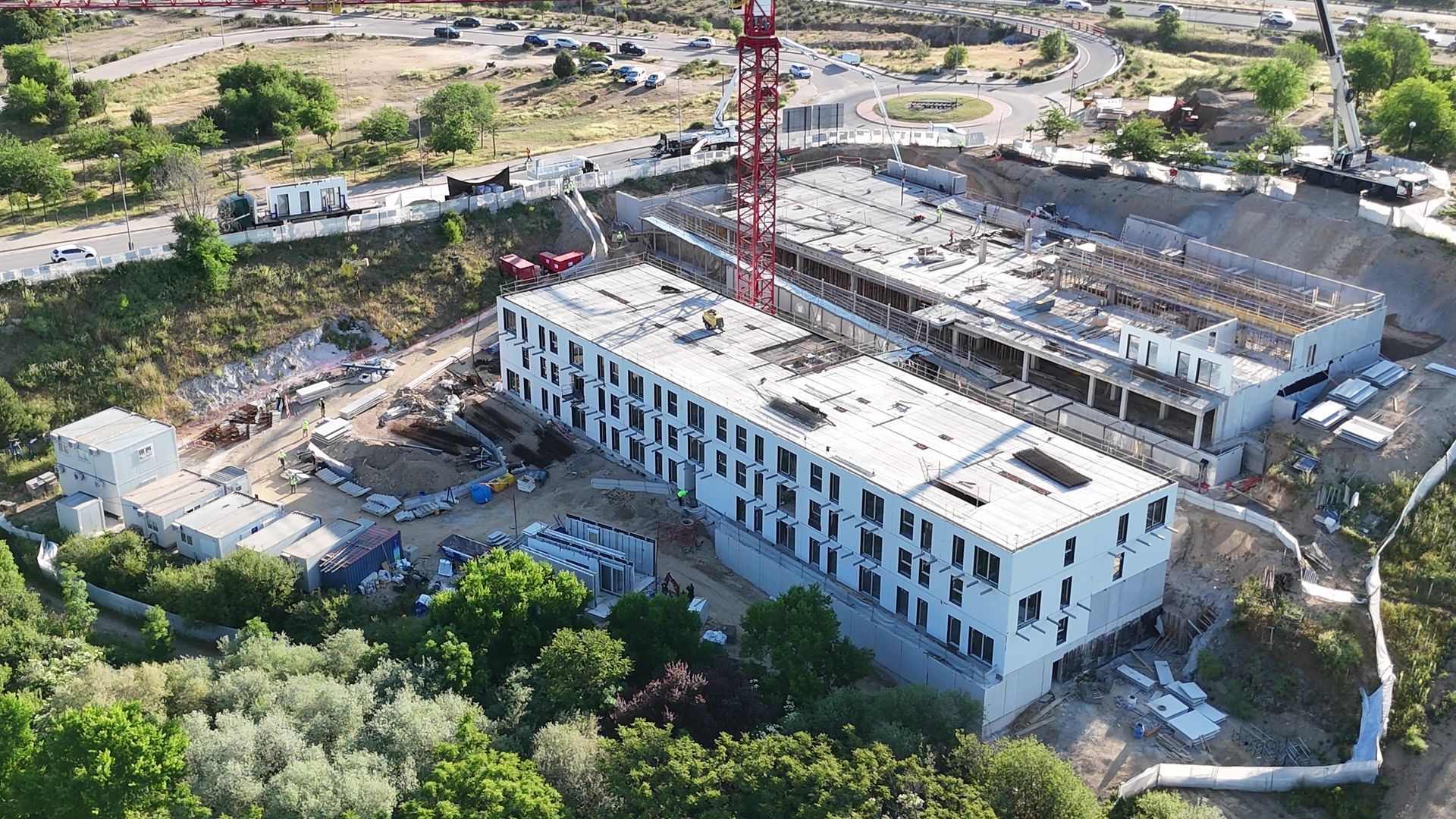 Sitio de construcción, edificio en construcción, grúa, árboles, día nublado.