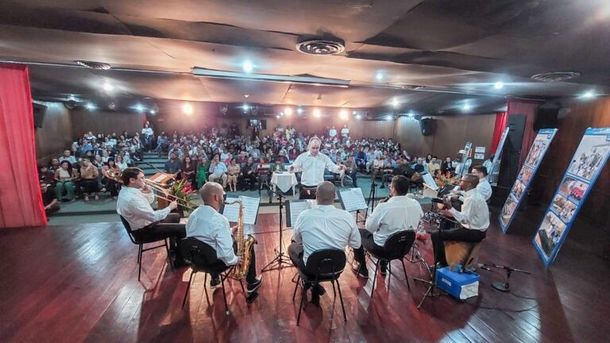 Um grupo de homens está tocando instrumentos em uma sala grande.