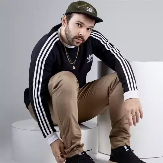 Um homem usando um chapéu e um suéter está ajoelhado