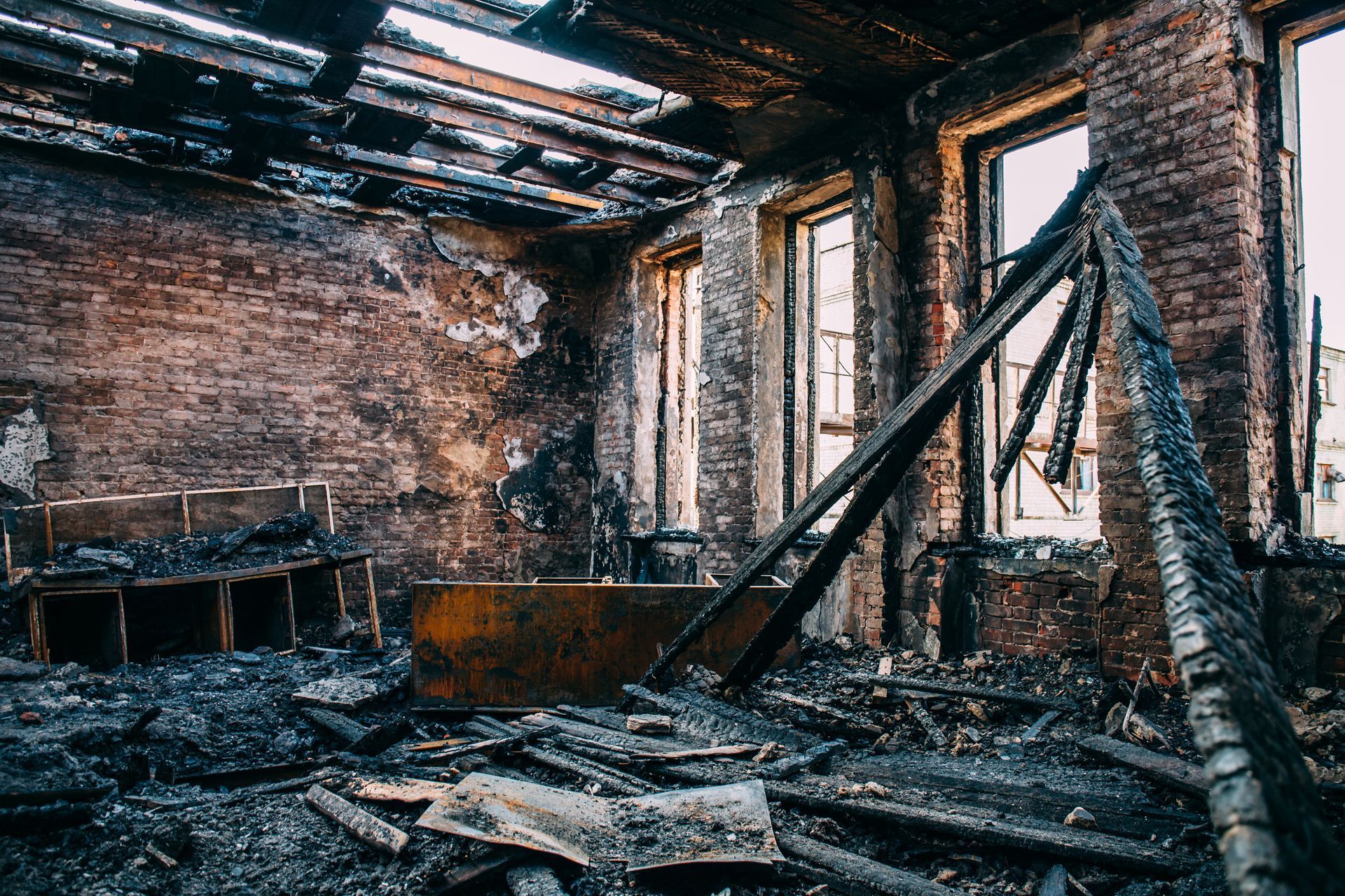 Interior of a room destroyed by fire; charred walls, broken debris, and window frames visible. Interior of a room destroyed by fire; charred walls, broken debris, and window frames visible.
