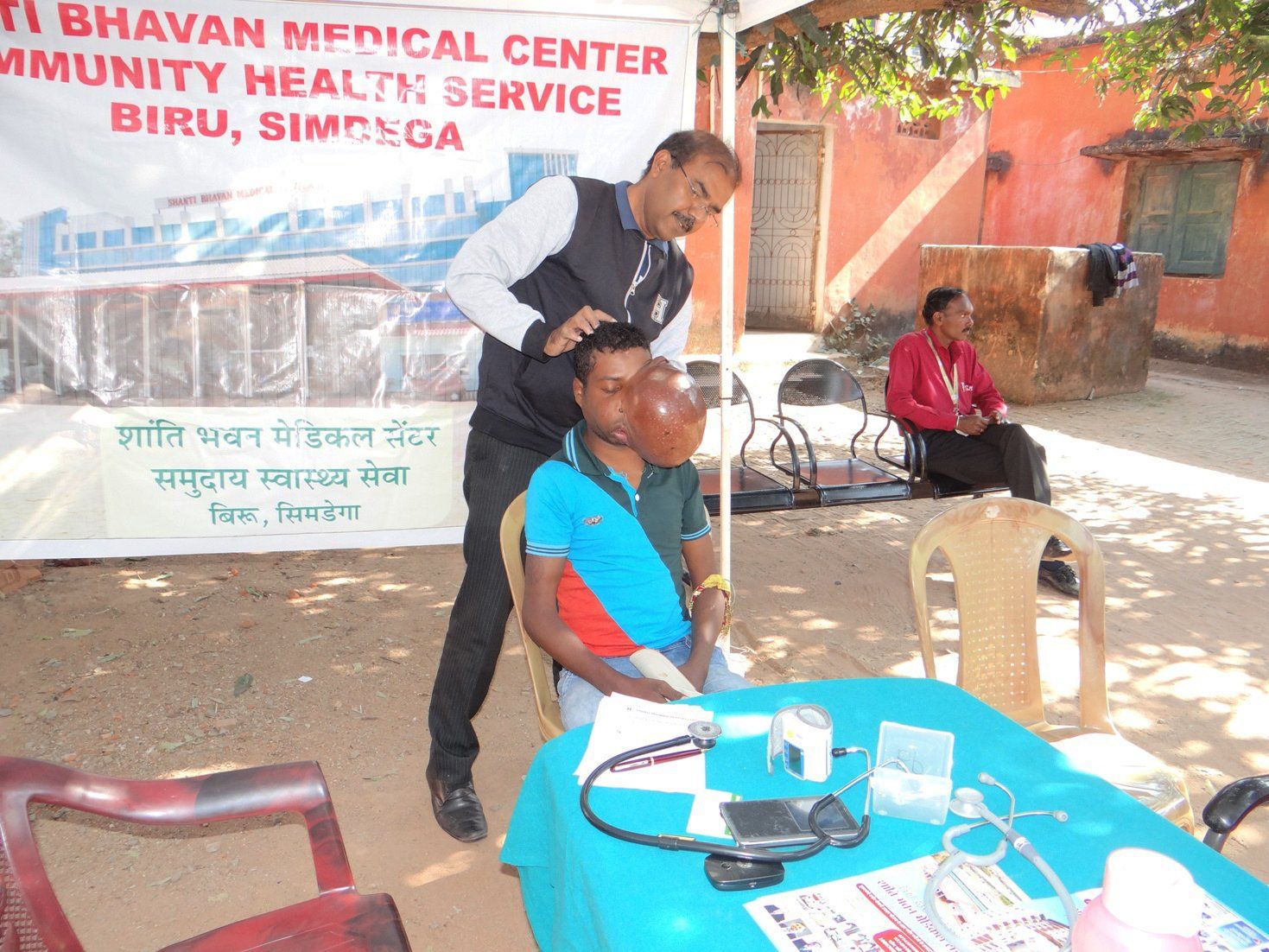 A man is examining another man 's face at a medical center