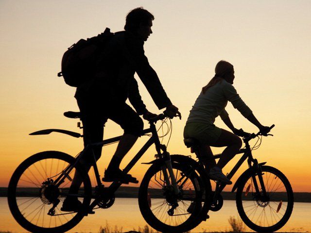 Bikers riding along the lake at sunset